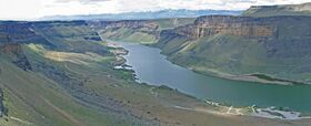 Wide view over a river valley surrounded by cliffs and shrub land