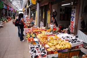 A female customer browsing a fruit shop. Banana and grapes are displayed on the front.