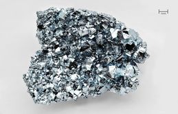 A silvery thumbnail-size chunk of osmium with a highly irregular crystalline surface.