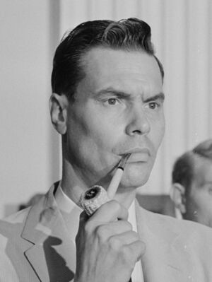 Black-and-white head shot of Rockwell holding a corncob pipe