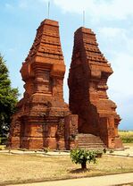 Two tall, brown, wavy structures facing each other, with a gap between that allows people to pass through.