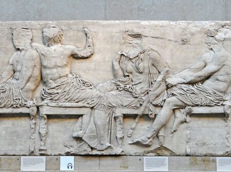 Four large, seated figures, with faces missing