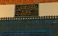 (اضغط للتكبير) اللوحة المكتوبة فوق "المقصورة السلطانية" والتي تذكر اسم مصمم الزخارف بالجامع وسنة انتهاء أعمال الزخرفة: "قد تم نقش هذه العمارة الشريفة بيد أفقر الناس علي بن إلياس علي" "في أواخر رمضـــان المبارك سنــة سبع وعشــــرون وثمانمائـــة"