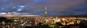 A photo of a large city by night. There is a high tower in its center.