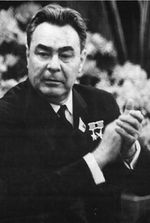 A grim-faced heavyset man claps his hands.