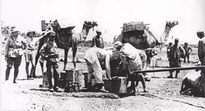 Three soldiers look on while Egyptian workers fill a water fantasie from a pipe