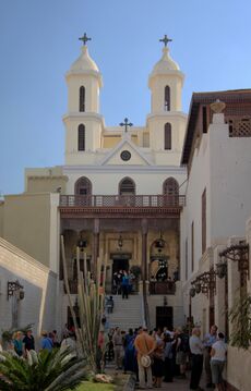 Exterior view of church facade showing twin bell towers with tourists gathered in front