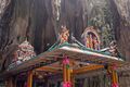 Four-pillared structure with religious statues on the roof in front of a rock wall inside the cave.
