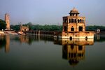 A pavilion and a wall above a pond, a large tower on the left