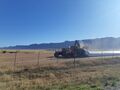 Two tractors deploying a sealed storage method for newly harvested wheat.