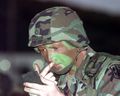 A soldier applying a disruptive pattern to his face; his helmet and jacket are both disruptively patterned