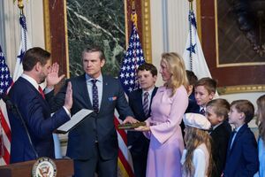 Two men in suits raising their right arms while children in suits and a woman in a pink outfit watch