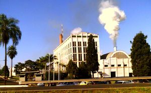 Photo of shorter building with smoke coming out of smokestack next to 5 story office building