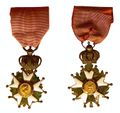 Late Empire Légionnaire insignia: the front features Napoleon's profile and the rear, the imperial Eagle. An imperial crown joins the cross and the ribbon.