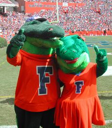 Two alligator mascots with their arms wrapped around each other posing for a photo.