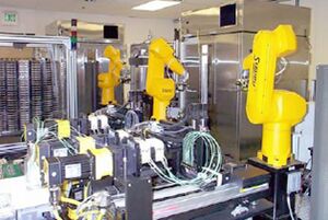 Photograph of robot equipped with liquid dispensing arms and loaded with 96 well plates.