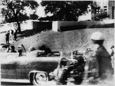 John F. Kennedy is fatally shot in the head, with Jacqueline Kennedy sitting beside him. Jacqueline can be seen turning over and looking at him at that moment.