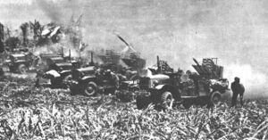 a row of trucks firing rockets. A cloud of dust is behind them.