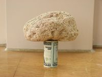 A 15-سنتيمتر (5.9 in) piece of pumice supported by a rolled-up U.S. 20-dollar bill demonstrates its very low density.