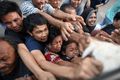 Survivors scuffle for live chickens being distributed from a police truck in Palu on October 2.jpg