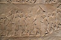 أسرى نوبيون يرافقهم حراس آشوريون خارج المدينة المصرية.[28]