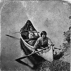 Three or four dark haired women near the shore in a canoe