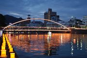 精霊流し：夜の水面に照り返す幻想的な光、左に無数の灯籠
